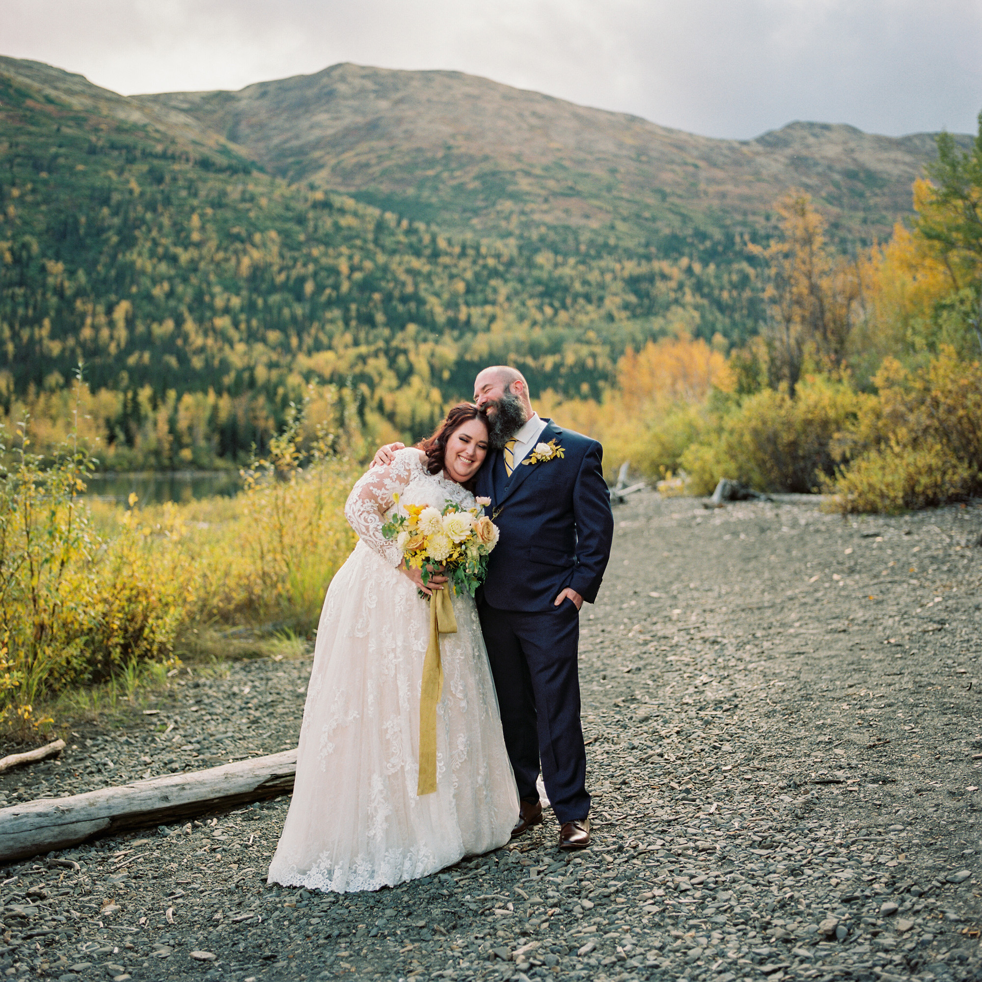 A beautiful couple standing on the lake shore of Eklutna Lake after their wedding ceremony.